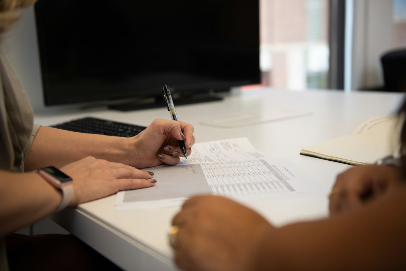 Close-up of two people reviewing a printed contract with a pen